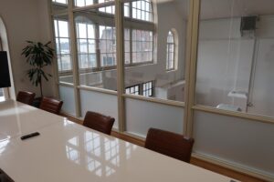Vergaderruimte met leren stoelen, witte tafel en groot raam met uitzicht op het Gedempt Hamerkanaal.